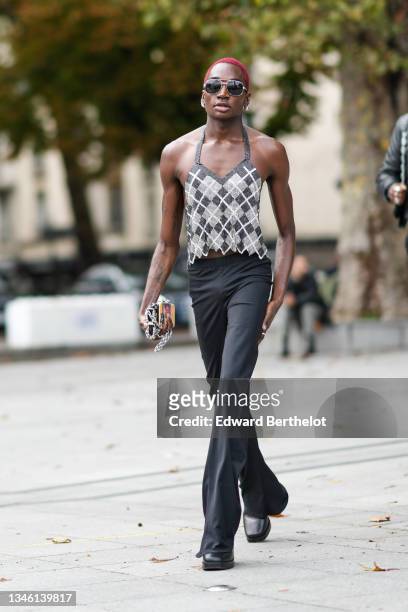 Guest wears sunglasses, silver earrings, a black and silver checkered pattern sequined V-neck tank-top, high waist black flared pants, a silver chain...