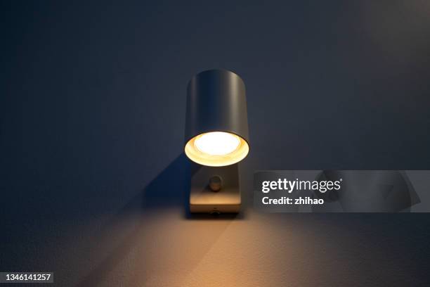 wall lamp illuminates the black wall - sconce stock pictures, royalty-free photos & images