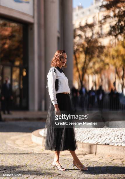 Alexa Chung wearing a black skirt and a white pullover outside Miu Miu Show on October 05, 2021 in Paris, France.