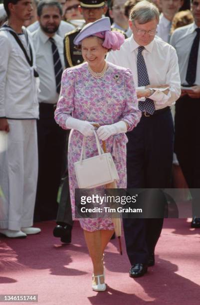 British Royal Queen Elizabeth II, wearing a pink, white and purple floral pattern outfit with a Frederick Fox hat, attends a garden party at Eden...