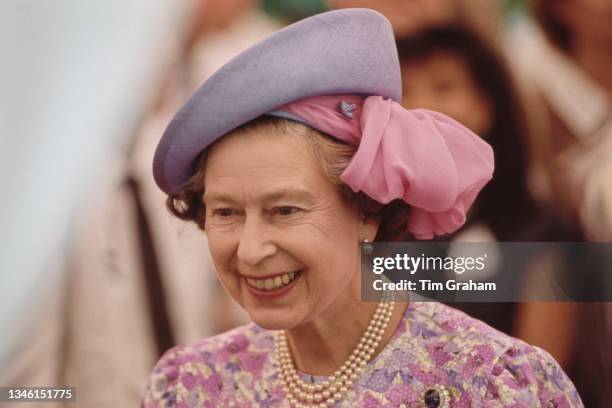 British Royal Queen Elizabeth II, wearing a pink, white and purple floral pattern outfit with a Frederick Fox hat, attends a garden party at Eden...