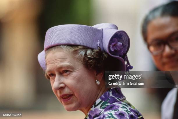 British Royal Queen Elizabeth ll, wearing a lilac, green and white outfit with a Philip Somerville hat, during a visit to the Tanjong Pagar...