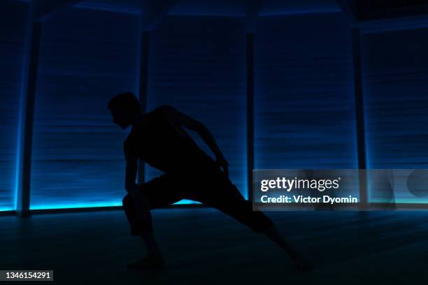 fit young man doing exercises in the dark studio - ninja warrior gym photos et images de collection