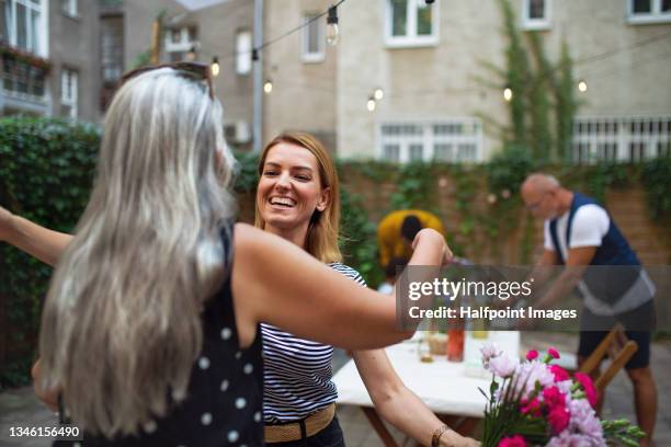 happy adult daughter with bouquet is about to hug her senior mother outdoors in garden. - surprised mum stock pictures, royalty-free photos & images