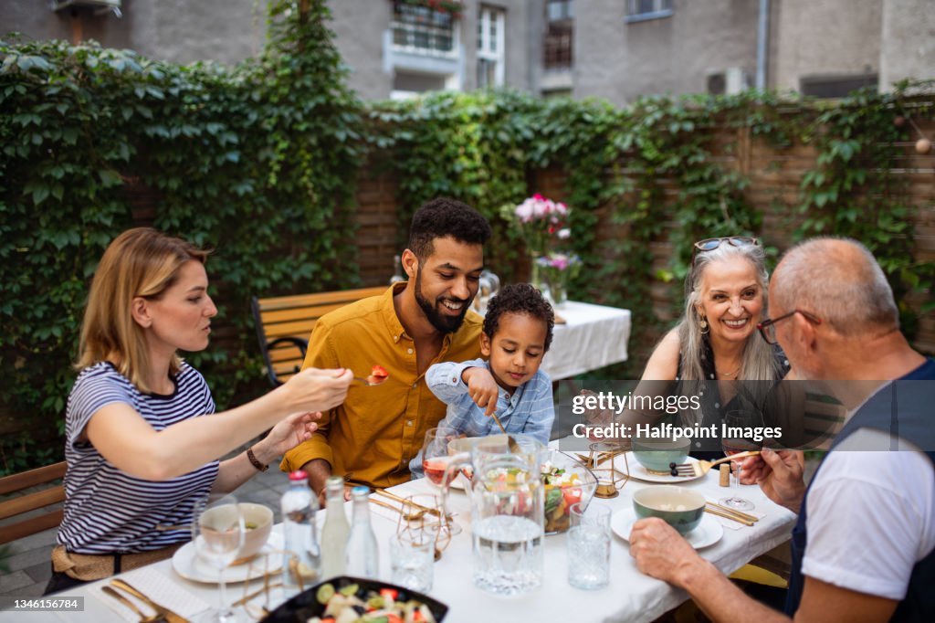 Portrait of multiracial three generations family having dinner together outdoors in front or back yard.