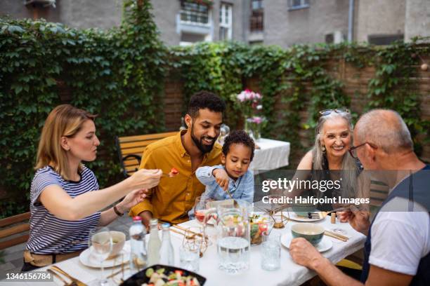 portrait of multiracial three generations family having dinner together outdoors in front or back yard. - family and happiness and diverse ストックフォトと画像