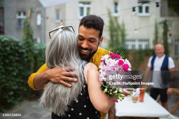 happy african american man with bouquet hugging his senior mother in law outdoors in garden. - flower presents bildbanksfoton och bilder