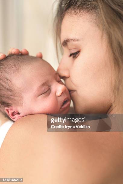 happy young mother is kissing the adorable newborn baby. - chest kissing stockfoto's en -beelden