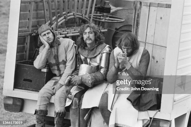 From left to right, actors Neil Innes , Eric Idle and Graham Chapman on the set of the comedy film 'Monty Python and the Holy Grail', UK, May 1974.