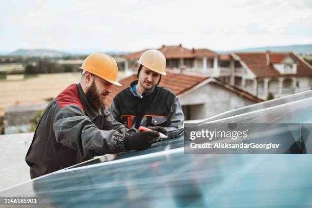 zwei arbeiter messen und dokumentieren die abmessungen von photovoltaikzellen von solarmodulen - wiederbelebung stock-fotos und bilder