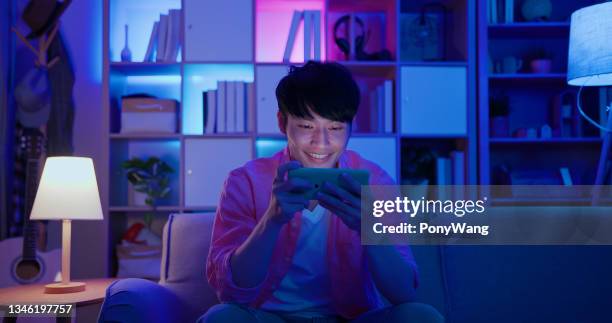 uomo gioca giochi mobili - man couch foto e immagini stock