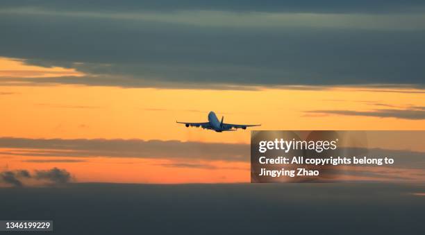 silhouette of a large cargo plane taking off in the sunset glow - plane taking off stock-fotos und bilder
