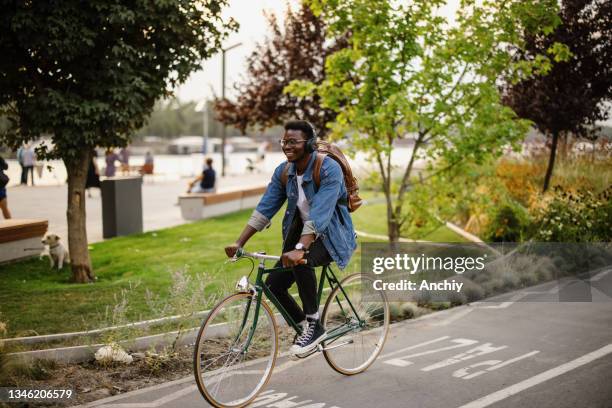 young man cycling down the street - black alley stock pictures, royalty-free photos & images