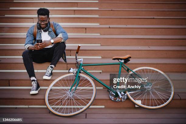 bicycle commuter taking a break and looking at his phone - black alley stock pictures, royalty-free photos & images