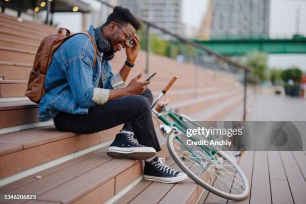 bicycle commuter taking a break and looking at his phone - black alley stock pictures, royalty-free photos & images