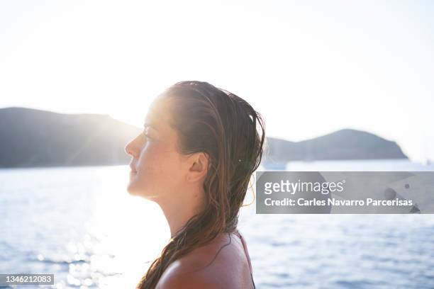 rays of the sun illuminating a blonde wet woman during sunset in the sea - hot women on boats stock pictures, royalty-free photos & images