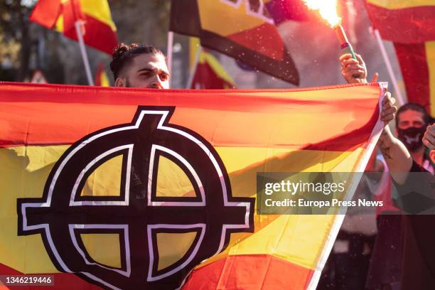Young man carries the flag of Spain with a Nazi symbol printed on it during a neo-Nazi demonstration to celebrate Columbus Day, October 12 in...