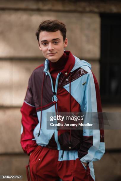 Noah Schnapp wearing a blue, red and brown colored jacket and pants outside Lacoste Show on October 05, 2021 in Paris, France.