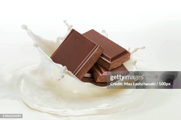 close-up of chocolate splashing in bowl against white background - milk stream stock pictures, royalty-free photos & images