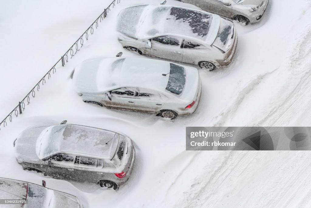 Top view of snow covered cars in street parking lot