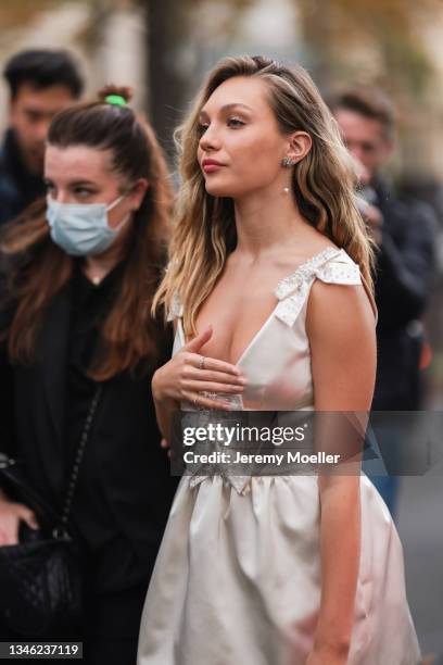 Maddie Ziegler wearing a white dress and a white bag outside Miu Miu Show on October 05, 2021 in Paris, France.