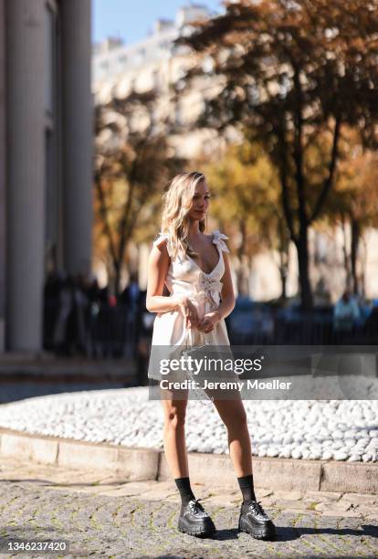 Maddie Ziegler wearing a white dress, a white bag and black boots outside Miu Miu Show on October 05, 2021 in Paris, France.