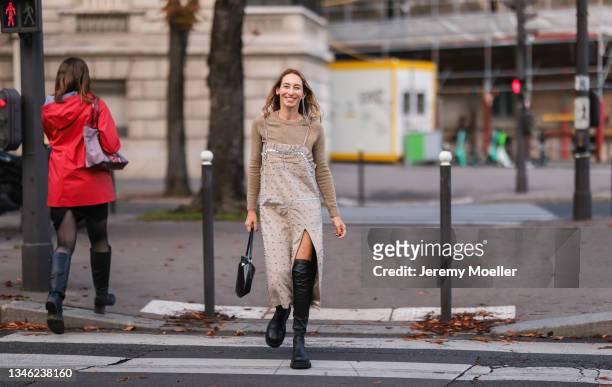 Alexandra Golovanoff wearing a beige dress and black boots outside Miu Miu Show on October 05, 2021 in Paris, France.