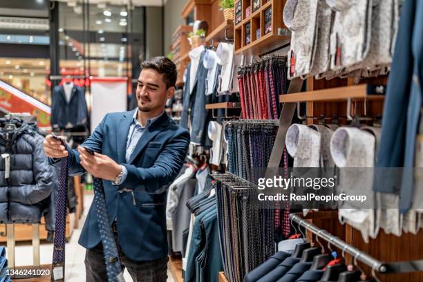 retrato de un joven guapo comprando ropa en la tienda. - abrigo blanco artículo de moda fotografías e imágenes de stock