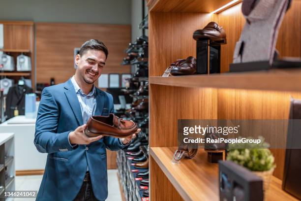 man  choosing classic shoes while doing shopping in the male store - shoe shopping stock pictures, royalty-free photos & images