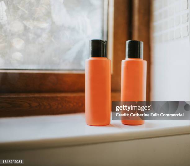 two shampoo bottles sitting on a tiled windowsill - shampoo bildbanksfoton och bilder