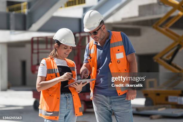 civil engineers checking works according to project using digital tablet at construction site - civilperson stock pictures, royalty-free photos & images