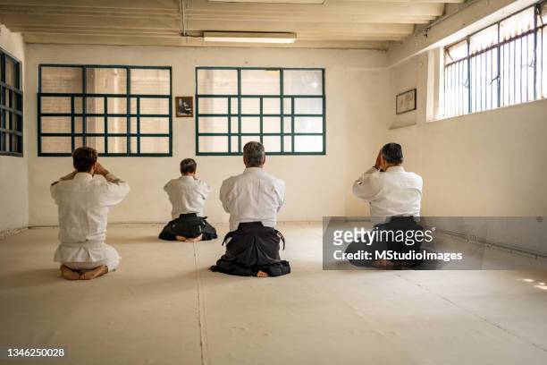 four people meditating before aikido training - japanese martial arts stock pictures, royalty-free photos & images