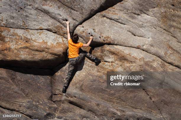 young rock climber clambering overhanging stone wall outdoors - überhängend stock-fotos und bilder