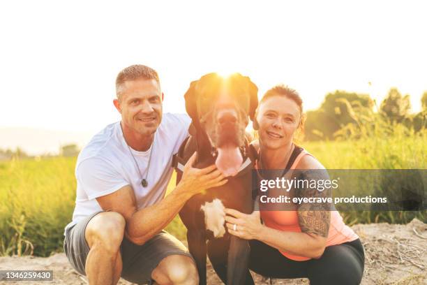 healthy fit body-builder couple walking and playing with black great dane dog in rural western usa at golden hour photo series - great dane home stock pictures, royalty-free photos & images