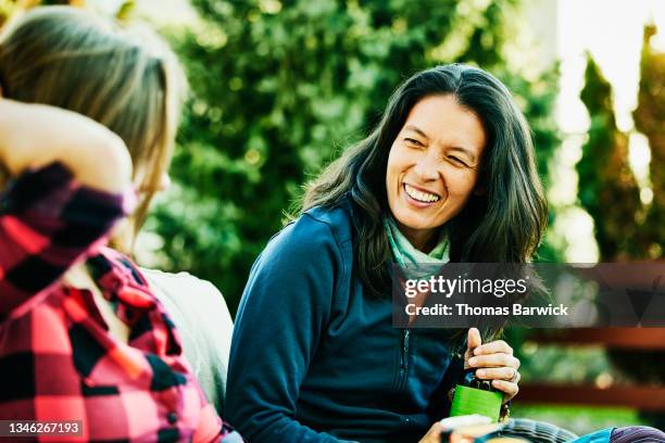 medium wide shot of laughing woman sharing drinks with friends in backyard - asian woman beauty shot photos et images de collection