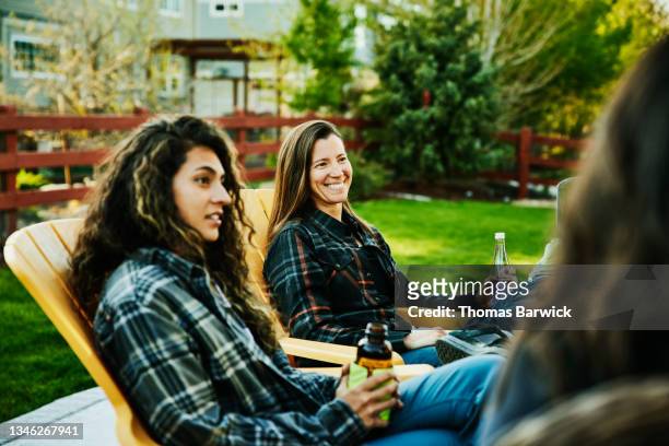 medium wide shot of smiling female friends sharing drinks in backyard - medium group of people foto e immagini stock