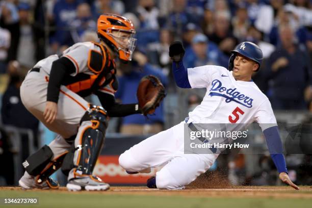 Corey Seager of the Los Angeles Dodgers scores against Buster Posey of the San Francisco Giants on a double by Trea Turner during the first inning in...