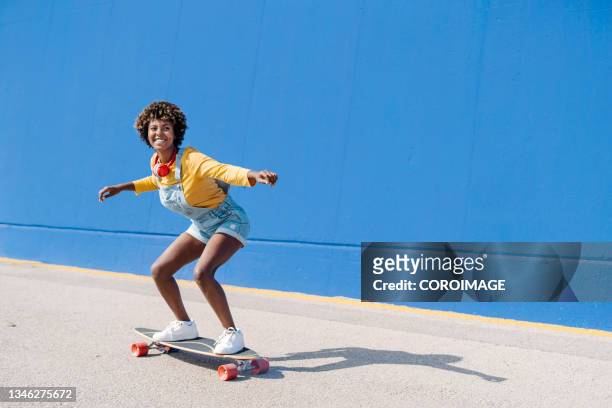 happy afro woman having fun while enjoying skateboarding outdoors on the city street. - skate foto e immagini stock