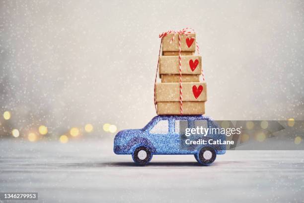 cute blue glitter car driving in snow with christmas gifts on roof - christmas driving stockfoto's en -beelden