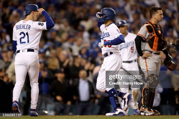 Mookie Betts celebrates his two run home run with Walker Buehler of the Los Angeles Dodgers in front of Buster Posey of the San Francisco Giants...