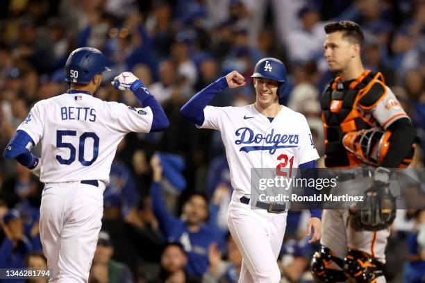 Mookie Betts celebrates his two run home run with Walker Buehler of the Los Angeles Dodgers in front of Buster Posey of the San Francisco Giants...