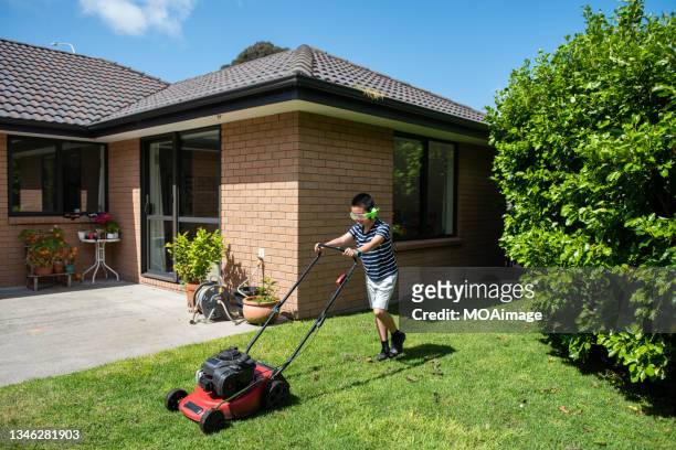 teenage boy wearing headphones mowing lawn in backyard - mowing lawn stock pictures, royalty-free photos & images