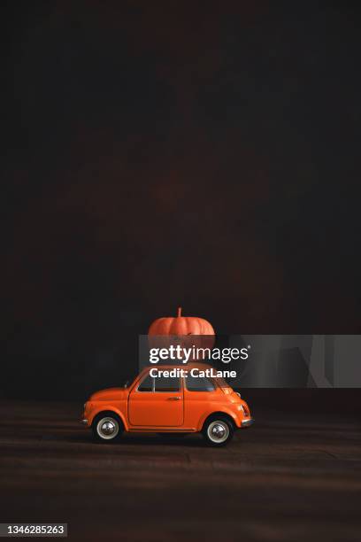small orange car with pumpkin on roof - cute small cars stock pictures, royalty-free photos & images