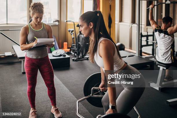 fitness trainer watching a woman training - personal trainer stock pictures, royalty-free photos & images