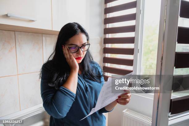 worried woman checking bills at home - energy bill stockfoto's en -beelden