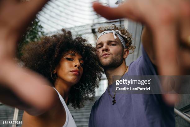 alternative couple of street dancers in urban clothes posing in city downtown - rappare bildbanksfoton och bilder