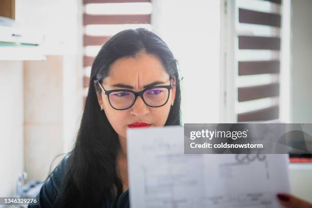 worried woman checking bills at home - energy bill stock pictures, royalty-free photos & images