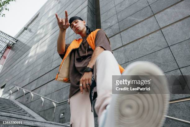 alternative man dressing urban clothes posing in city downtown - rapper stock pictures, royalty-free photos & images
