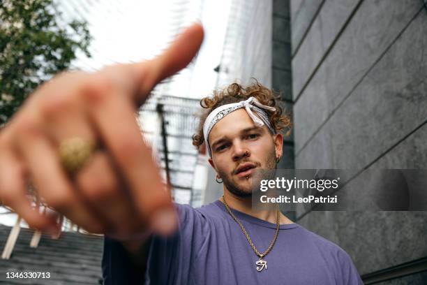alternative man dressing urban clothes posing in city downtown - nas rapper imagens e fotografias de stock
