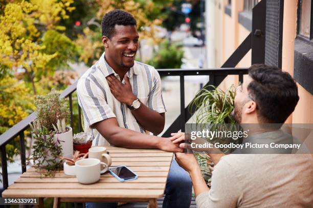 hombre gay proponiéndole matrimonio a su pareja sorprendida en su balcón - prometido fotografías e imágenes de stock